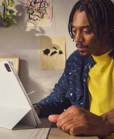 一位男子在办公室使用银色 12.9 英寸 iPad Pro。