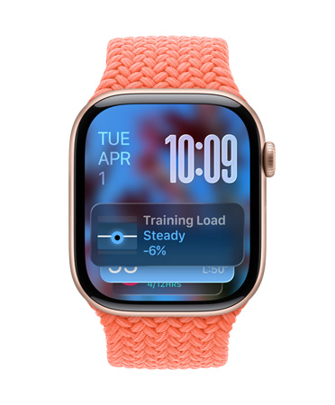 玫瑰金色 Apple Watch 搭配橘红色编织表带，表盘左上角显示日期，右上角有数字显示时间，下方为训练负荷小组件，全部采用半透明 Liquid Glass 设计。